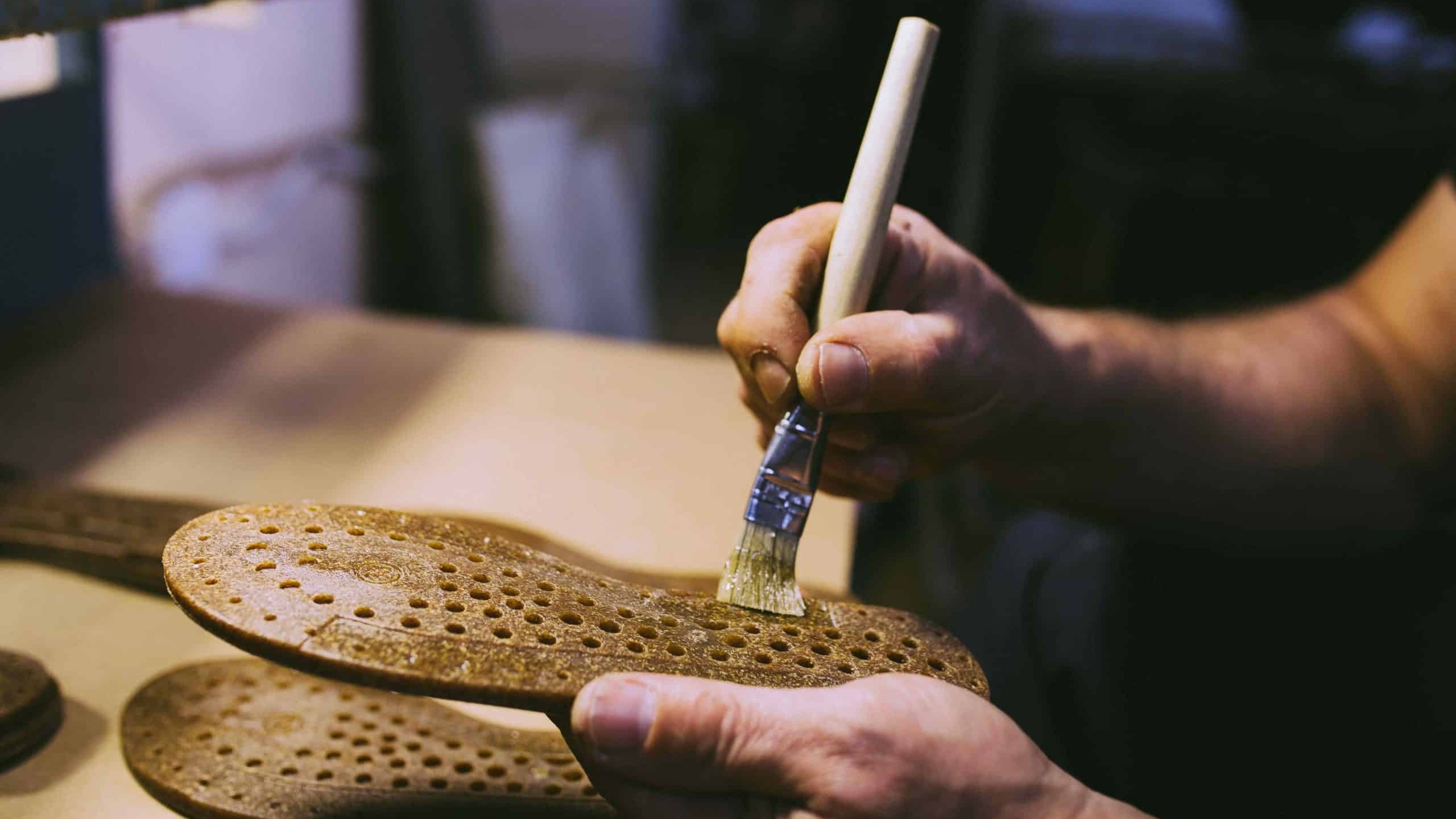 Cordonnier qui applique de la colle sur une semelle de chaussure en cuir